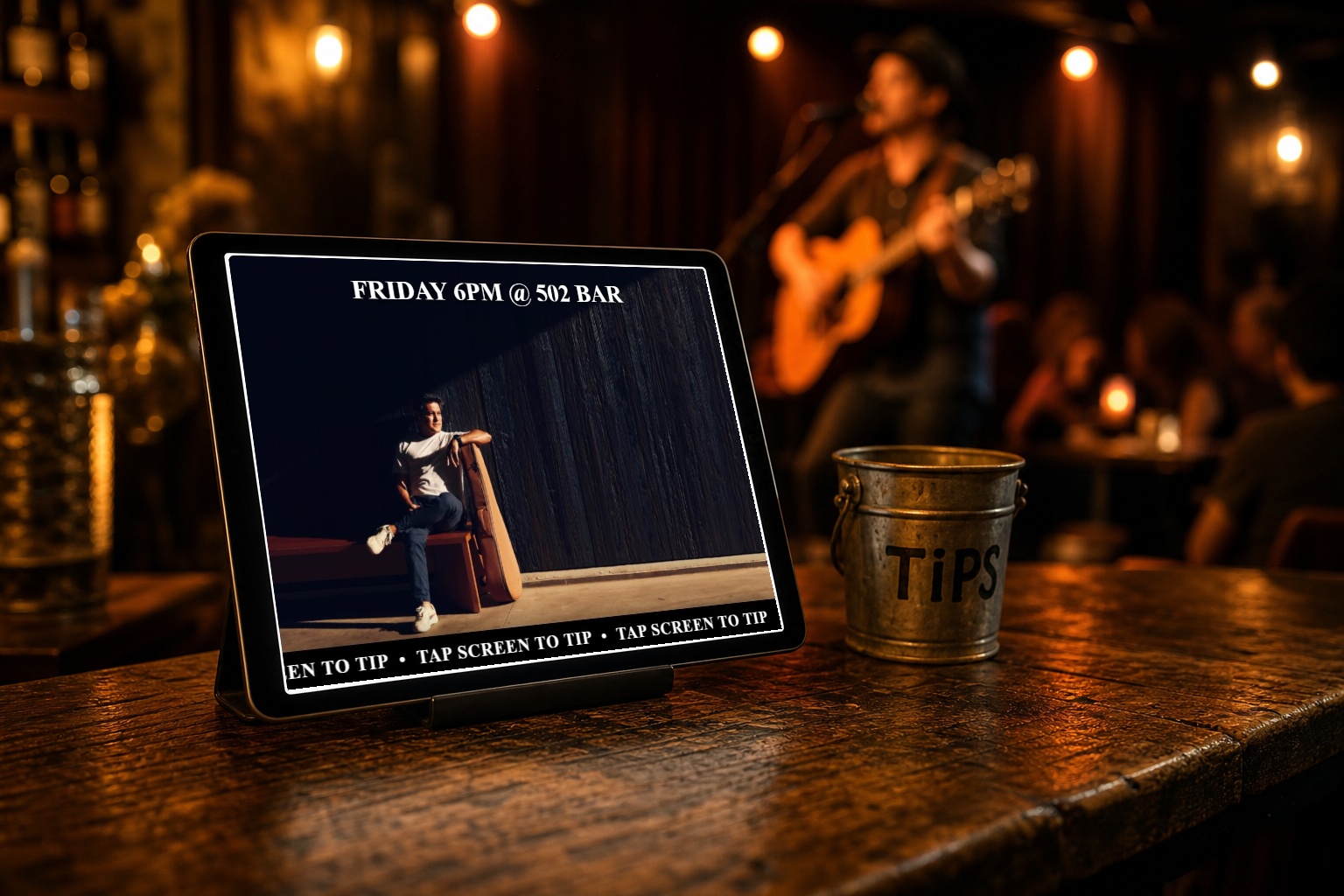 Tablet running a Digital Tip Station slide with a Tap Screen to Tip bar beside a tip jar at a live music gig